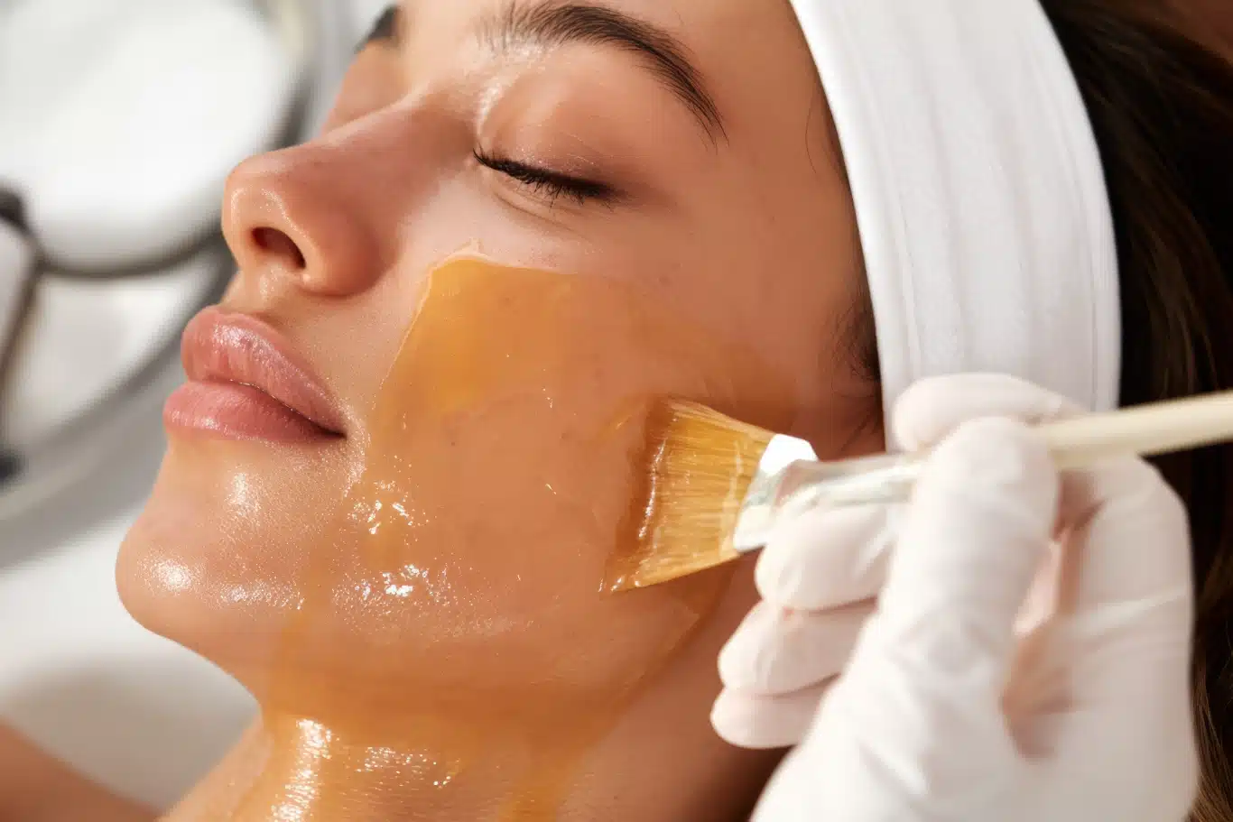 Chemical peel facial treatment procedure in a salon Facial treatment with brush applying golden face mask